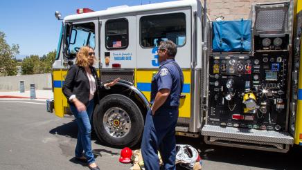 Asm. Irwin speaking with fireman in front of fire truck