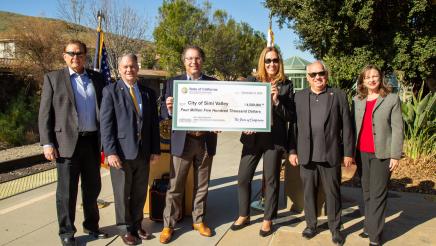 Group photo with large ceremonial check held at center