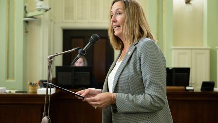 Asm. Irwin standing on the Assembly Floor holding folder, speaking into microphone