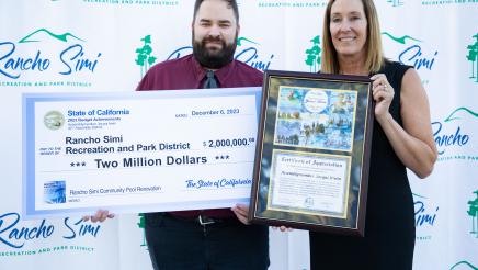 Asm. Irwin holding up award, with city official holding up check