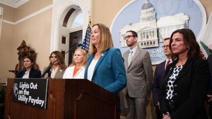 Asm. Irwin at podium, speaking, with other legislators on either side