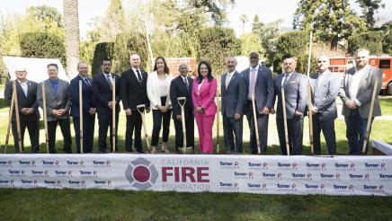 Group photo of Asm. Irwin and other attendees, with large banner in foreground