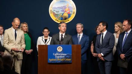 Attorney General Rob Bonta at podium, speaking, with legislators standing in support