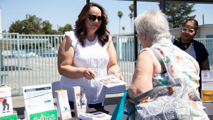 Table staffer speaking with constituent and offering informational materials