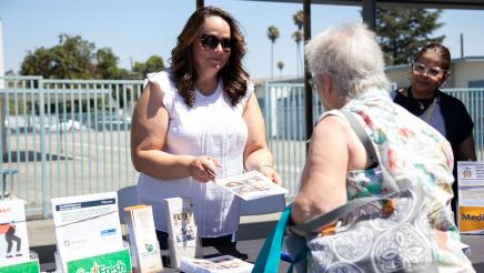 Table staffer speaking with constituent and offering informational materials