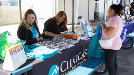 Clinicas table staffers conversing with constituent