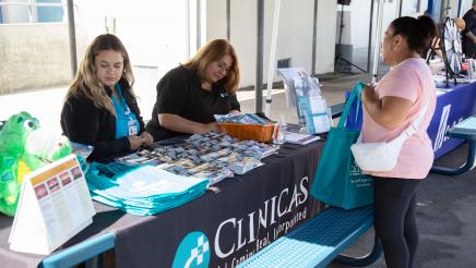 Clinicas table staffers conversing with constituent