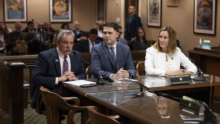 Witness providing testimony as fellow witness and Asm. Irwin listen on