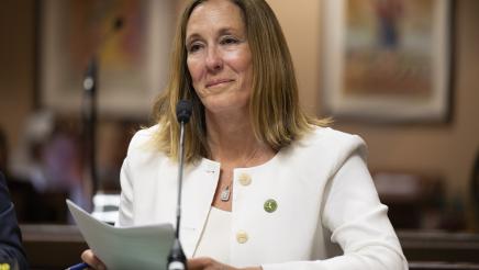 Asm. Irwin holding documents while providing testimony