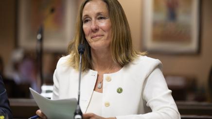 Asm. Irwin holding documents while providing testimony